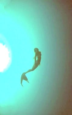 a person is swimming in the water under a bright blue sky with a sun behind them