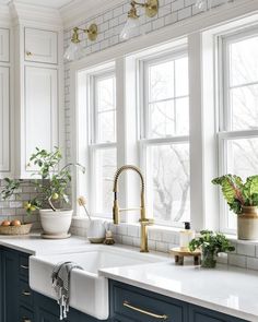 a kitchen with blue cabinets, white counter tops and gold faucets on the windowsill