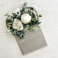 white flowers and greenery are placed on top of a gray book with writing that says love