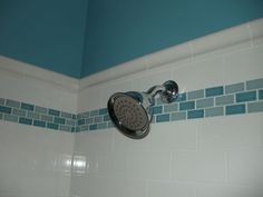 a shower head with blue and white tiles on the wall