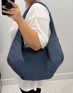 a woman taking a selfie with her cell phone while wearing a crochet bag