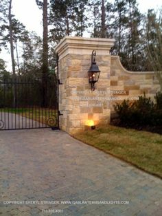 a gated entrance to a home with a light at the end and an iron fence around it