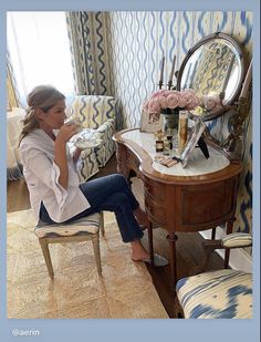 a woman sitting on a chair in front of a vanity