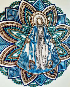 the virgin mary in blue and gold on a white background with an intricate pattern around it