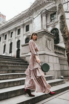 a woman in a polka dot dress is walking down the steps with a black pan