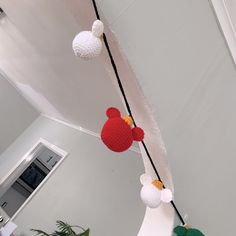 some balls are hanging from a rope in a room with white walls and flooring