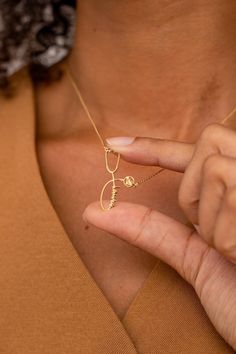 a woman holding onto a gold necklace with the letter c on it's side