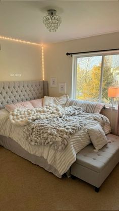 a bedroom with a large bed covered in blankets and pillows, lights on the wall