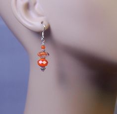 Three interesting different orange glass beads, Swarovski crystal and Bali sterling silver beads are featured in these unique pierced earrings. All metal is 925 sterling silver. Each earring weighs 2.4 grams as compared to a US dime weighing 2.268 grams. All metal is sterling silver. For questions and or requests feel free to contact me. Thank You for looking. Orange Czech Glass Jewelry With Ear Wire, Nickel Free Carnelian Orange Earrings, Orange Sterling Silver Jewelry With Round Beads, Orange Jewelry With Silver Beads As A Gift, Orange Jewelry With Silver Beads For Gift, Nickel-free Orange Beaded Drop Earrings, Orange Faceted Beads Dangle Earrings, Orange Faceted Beads Earrings For Gifts, Orange Faceted Beaded Earrings For Gift