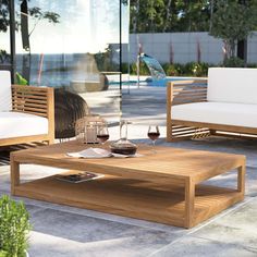 a wooden coffee table sitting on top of a cement floor next to a white couch