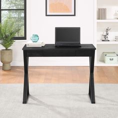 a black desk with a laptop on it in front of a white wall and window