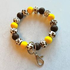 a close up of a bracelet on a white surface with black, yellow and brown beads