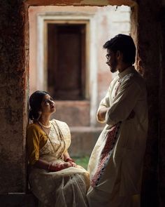 a man and woman standing next to each other in front of an open doorway,