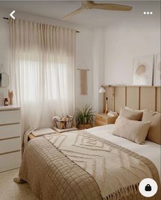 a bed room with a neatly made bed next to a window and a plant in the corner