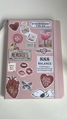 a pink notebook covered in stickers and magnets next to a pair of scissors