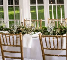 the table is set with white linens and greenery