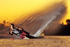 a man riding skis on top of a body of water next to a wave