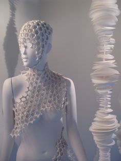 a white mannequin with chains on it's neck and head in front of a wall