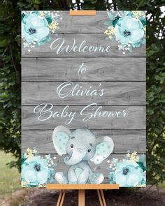 a welcome sign for a baby shower with an elephant and flowers on the front, sitting on top of a easel