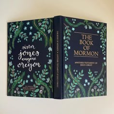 the book of mormon is open on a white surface with blue flowers and green leaves