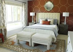 a bedroom with red walls and white bedding, two stools on either side of the bed