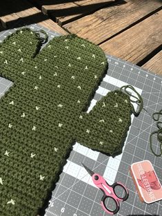 a crocheted cactus is sitting on a table next to scissors