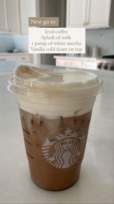 a cup of iced coffee sitting on top of a kitchen counter next to a sign that says, new go to iced coffee splash of milk