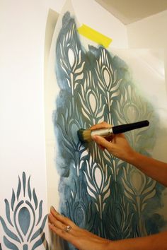 a person is using a brush to paint a peacock mural