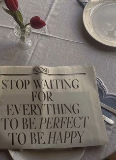 a newspaper sitting on top of a table next to a vase with flowers in it