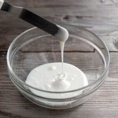 a glass bowl filled with white liquid on top of a wooden table