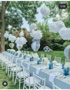 an outdoor table set up with blue and white tables cloths, balloons in the shape of hot air balloons