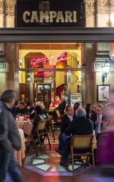 people sitting at tables in front of a restaurant