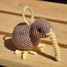 a small crocheted bird sitting on top of a wooden bench next to a string