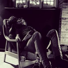 a man laying on top of a chair next to a woman in a black and white photo