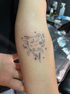 a woman's arm with a cat tattoo on the left side of her arm