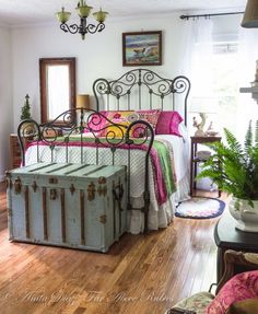 an old trunk as a bed frame in a bedroom with wood floors and white walls