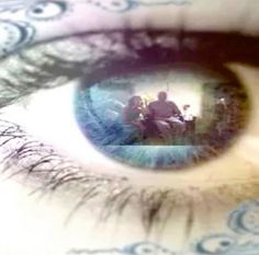 an eye with the reflection of two people sitting at a table in front of them