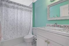 a white toilet sitting next to a bath tub under a bathroom mirror on top of a counter