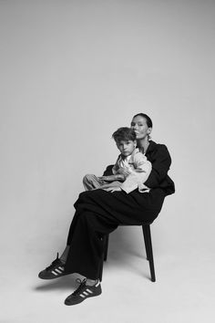 a woman sitting on top of a chair next to a young boy in black and white