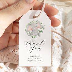 a hand holding a baby shower tag with an elephant on it's back and the words thank you