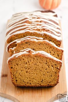 sliced loaf of pumpkin spice bread with icing on a cutting board next to an orange pumpkin