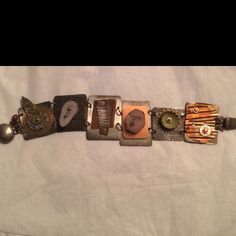 "I love making jewelry that has panels or individual pieces that I can create as individual little works of art.  Each of these 6 silver panels is approximately 1\" wide and 1-1.5\" high.  Each has a different set of created or found objects; including corrugate copper, enameled bead cap, polymer face cane, animal antler slice, and layered metal discs.  Cold connections are used primarily. There is a sterling silver clasp.  This is a real conversation piece.  All pieces are one of a kind." Silver Bracelet With Custom Hardware, Silver Metal Bracelet With Custom Hardware, Handmade Metal Fusion Bracelets, Artisan Soldered Metal Jewelry, Metallic Metal Bracelet, Metallic Metal Bracelet Jewelry, Artsy Bracelet With Unique Variations, Unique Silver Metal Bracelet, Artisan Metal Jewelry With Stamped Details