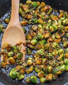 the brussel sprouts are being cooked in a skillet with a wooden spoon