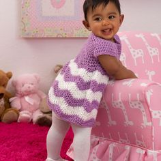 a small child is standing on a pink chair with stuffed animals in the room behind her