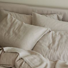 an unmade bed with white linens and pillows