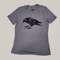 This is our Crow painting, screen printed in Black ink on Storm Gray tri-blend* tees. The Crow, drawn and printed for a farewell tribute of a dearly loved family friend, Eric Braun, 1976 - 2014. The Crow design has been modified a bit since that first memorial printing, but it still represents the love of family and friends Eric exuded in his every day life. Side seams Roomy crew neck True to size Feminine cut. Sarah is wearing a Medium in this same color and style (different design). *50% polye Vintage Hand Printed Short Sleeve T-shirt, Vintage Hand-printed Short Sleeve T-shirt, Memorial Graphic Print Short Sleeve T-shirt, Cotton Graphic Print T-shirt For Family Gatherings, Family Gathering Graphic Print Crew Neck T-shirt, Short Sleeve Tops With Graphic Print For Memorial, Graphic Print Short Sleeve Tops For Memorial, Memorial Crew Neck Tops With Graphic Print, Memorial Short Sleeve T-shirt With Graphic Print