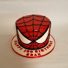 a spiderman cake with white and red icing on it's face is shown