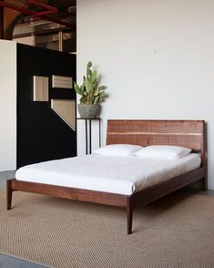 a bed sitting in the middle of a room next to a plant on top of a table