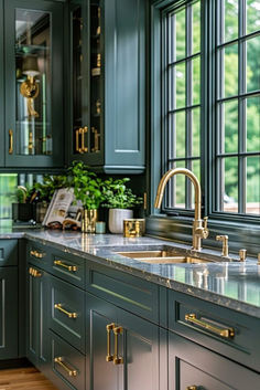 a kitchen with green cabinets and marble counter tops in front of a large window that looks out onto the woods