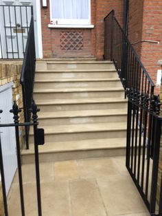 a set of stairs leading up to a brick building with wrought iron railings and handrails